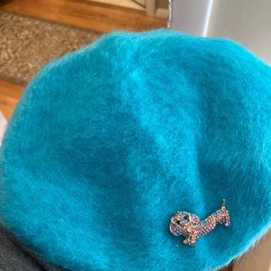 Normandy Ultrabasque Beret in teal with multicolored Dachshund pin attached.